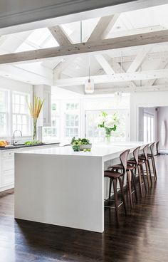 a large kitchen with an island and wooden floors in the center, along with several chairs