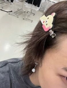 a girl with a bear hair clip in the middle of her head, looking down