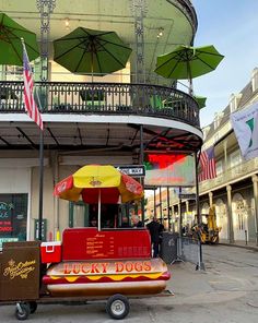 a hot dog cart with umbrellas on top in front of a building