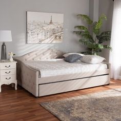 a bed sitting on top of a wooden floor next to a white dresser and lamp