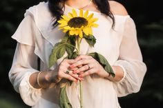 a woman holding a sunflower in her hands