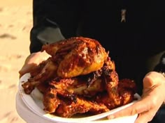 a person holding a white bowl filled with chicken wings