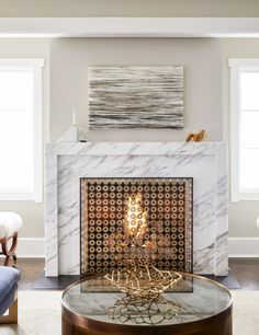 a living room with a fire place in the middle and a painting on the wall