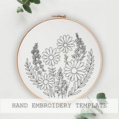 a hand embroidery pattern with daisies and leaves in the hoop on a white background