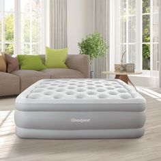 an inflatable mattress sitting on top of a wooden floor next to a couch