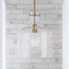 a glass bottle hanging from the side of a brick wall next to a light fixture