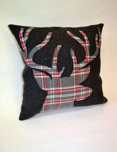 a black pillow with a plaid deer head on the front and antlers on the back