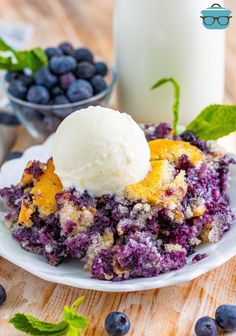 a blueberry cobbler with ice cream on top and fresh blueberries next to it