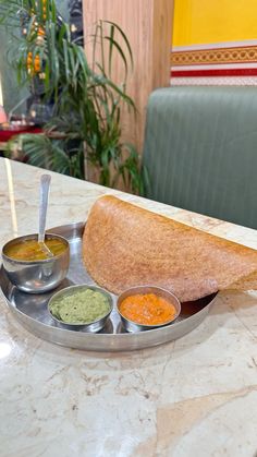 a plate that has some kind of bread on it with dipping sauces next to it