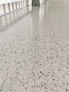 the floor in an airport has black dots on it and is white with gray walls