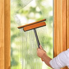 a person holding a mop in front of a window with water running down it