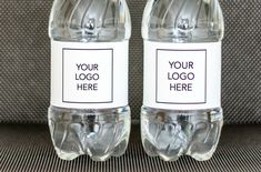 two bottled water bottles sitting next to each other on top of a gray cloth covered surface