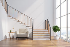 a white chair sitting in front of a stair case next to a wooden table with a potted plant on it