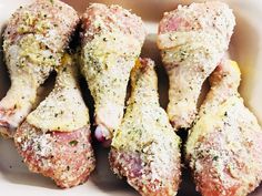 four pieces of meat covered in seasoning sit in a white bowl on a table