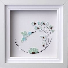 a white frame with some glass flowers in the middle and one flower on it's side