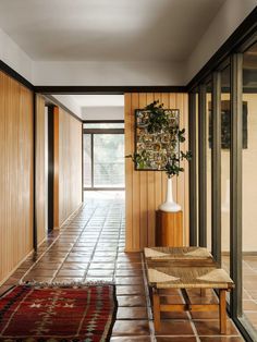 the hallway is lined with wooden paneled walls and flooring, along with a large rug