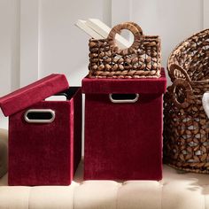 three red storage bins sitting on top of a couch next to a mirror and wicker basket