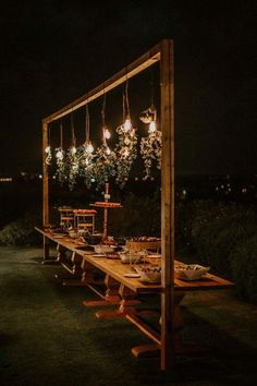 a long wooden table with lights hanging from it's sides and plates on top