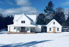 a large white house sitting on top of a snow covered field with trees in the background