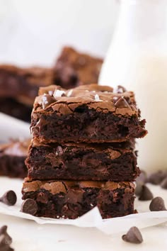 three chocolate brownies stacked on top of each other next to a glass of milk