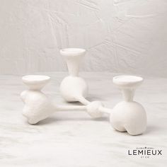 three white vases sitting next to each other on a table