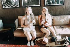 two beautiful women sitting on top of a couch