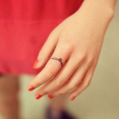 a woman's hand with a small ring on her left thumb and a cross tattoo on the middle finger