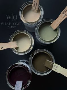 three cans of paint with wooden handles and labels on them