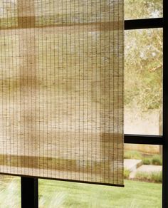 an open window with the blinds pulled back to let in light and shade on the grass