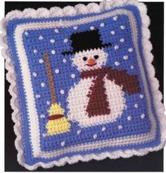 a crocheted snowman with a broom and hat on it's pillow