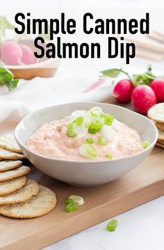 a white bowl filled with salmon dip surrounded by crackers and radishes on a cutting board