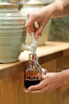 a person is pouring something into a small bottle with a spigot on it