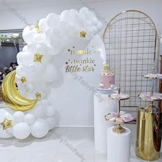 a balloon arch with stars and moon on it in the middle of a white room