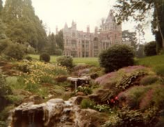 a large building sitting on top of a lush green hillside next to a forest filled with lots of trees