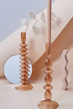 there are two candles that are standing next to each other on the table and one has a flower in it