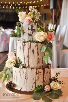 a three tiered cake with flowers and greenery on the top is sitting on a table