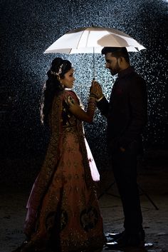 a man and woman standing under an umbrella in the rain