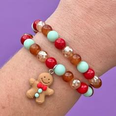 two bracelets that have different colored beads on each one and a teddy bear charm on the other