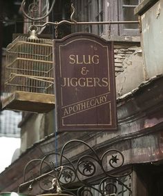 a sign for slug & jiggers apothecary hanging from the side of a building