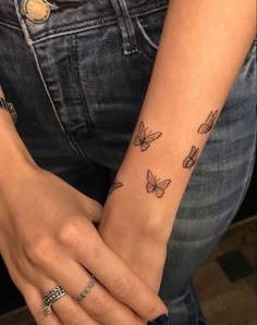 a woman's arm with butterfly tattoos on her left wrist and the other hand