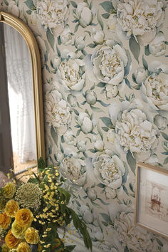 a vase filled with yellow flowers next to a mirror and framed photograph on the wall