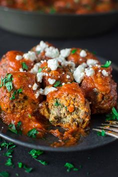 meatballs covered in marinara sauce and feta cheese on a plate with fork