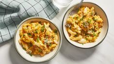 two bowls filled with macaroni and cheese on top of a white tablecloth