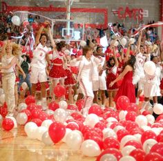 a group of young people standing on top of a basketball court surrounded by red and white balloons