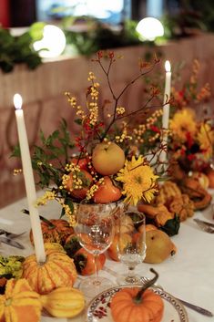 the table is set with pumpkins, gourds and flowers