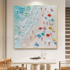 a painting hanging on the wall above a dining room table with chairs and an umbrella