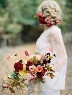 a woman holding a bouquet of flowers in her hand and wearing a white wedding dress