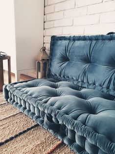 a blue couch sitting on top of a rug in front of a white brick wall