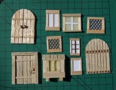 several pieces of wood are arranged on a green board with holes in the doors and windows