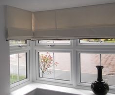 a black vase sitting on top of a window sill next to a white curtain